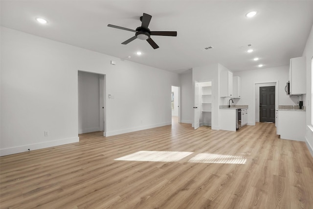 unfurnished living room with ceiling fan, sink, and light wood-type flooring