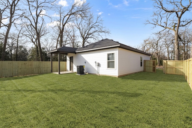 back of house with central AC unit and a yard