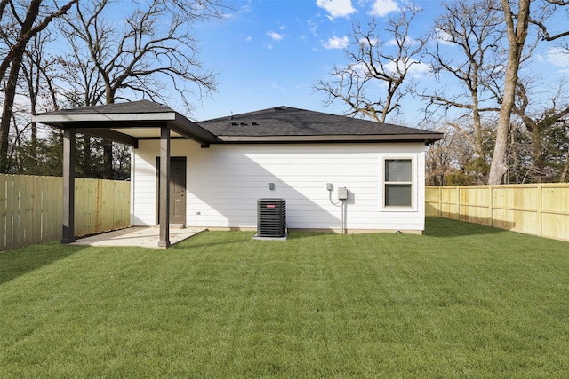 back of property with central AC unit, a patio area, and a lawn