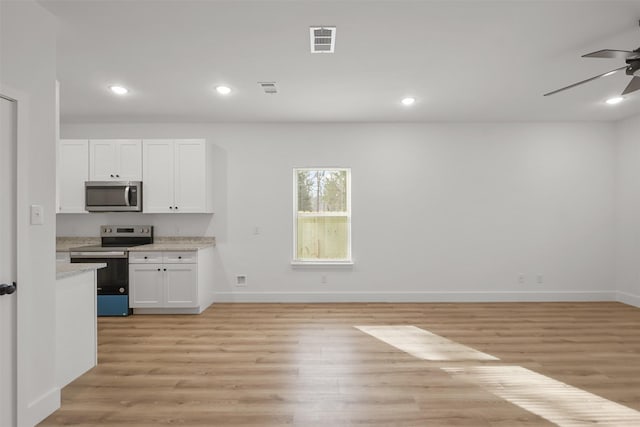 kitchen with white cabinets, appliances with stainless steel finishes, light hardwood / wood-style floors, ceiling fan, and light stone counters