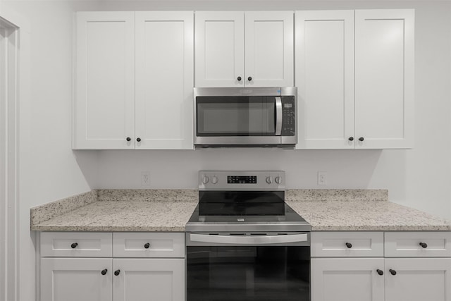 kitchen with light stone counters, white cabinets, and stainless steel appliances