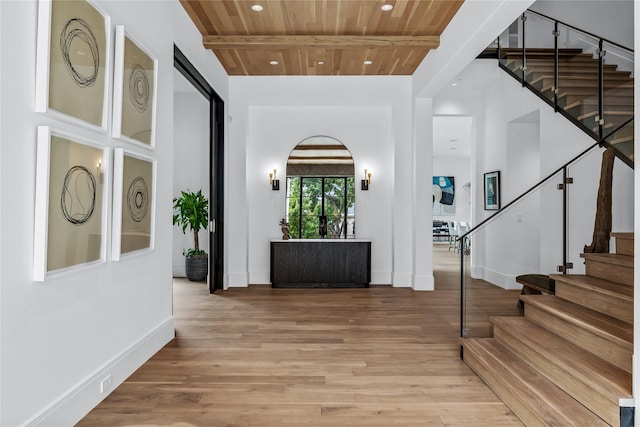 foyer with beam ceiling, wood ceiling, a high ceiling, and light hardwood / wood-style floors