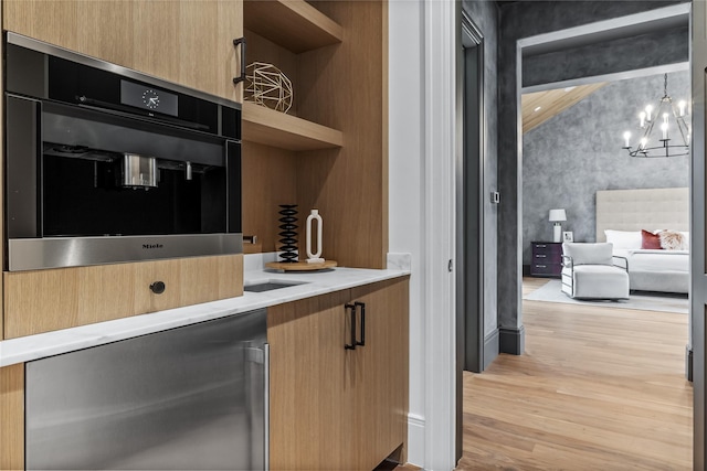 kitchen featuring decorative light fixtures, an inviting chandelier, oven, and light wood-type flooring