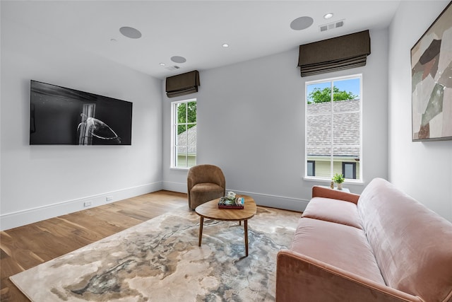 living room featuring a wall mounted AC and light hardwood / wood-style flooring