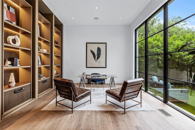 living area with built in features and light hardwood / wood-style flooring