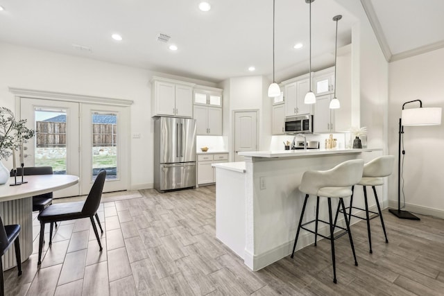 kitchen featuring decorative light fixtures, white cabinets, kitchen peninsula, and stainless steel appliances