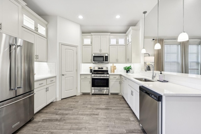 kitchen with white cabinets, stainless steel appliances, decorative backsplash, sink, and hanging light fixtures