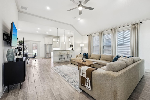 living room with vaulted ceiling, ceiling fan, a wealth of natural light, and ornamental molding