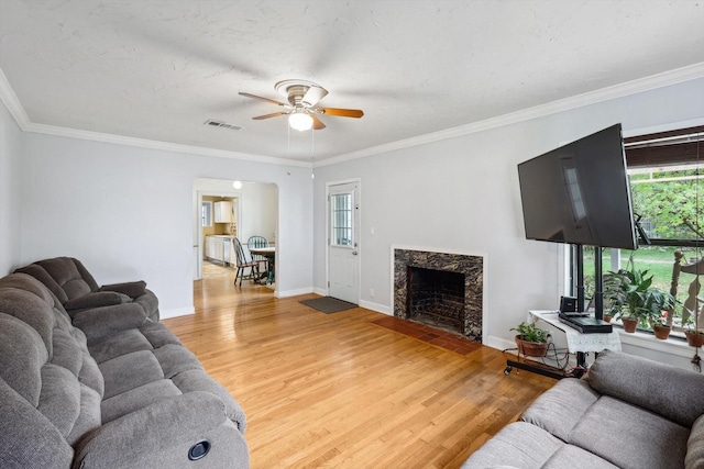 living room featuring hardwood / wood-style flooring, ornamental molding, and a premium fireplace