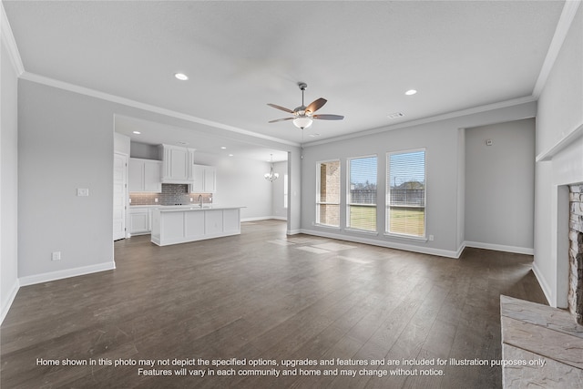 unfurnished living room with ceiling fan with notable chandelier, dark wood-style flooring, a fireplace, baseboards, and crown molding