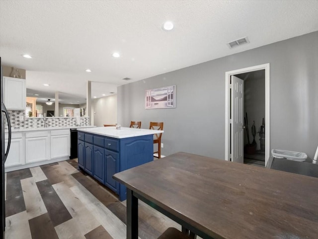 kitchen featuring kitchen peninsula, blue cabinetry, a breakfast bar area, a textured ceiling, and white cabinets