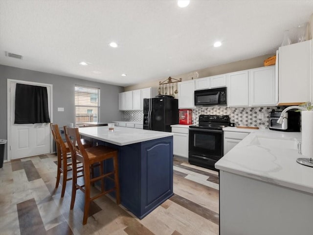 kitchen with white cabinets, a center island, backsplash, and black appliances