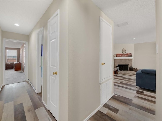 corridor with light hardwood / wood-style floors and a textured ceiling