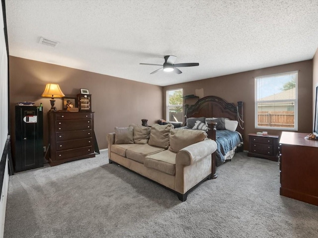 carpeted bedroom featuring ceiling fan and a textured ceiling