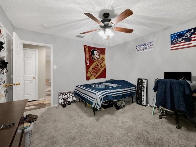 bedroom featuring a textured ceiling, ceiling fan, and carpet