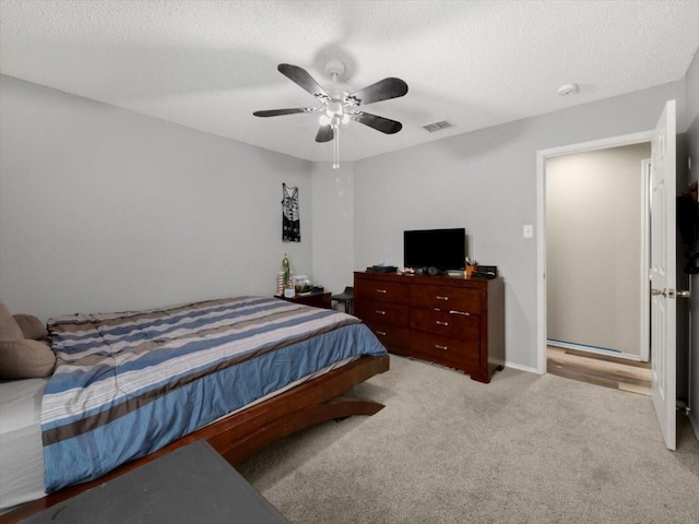 bedroom featuring ceiling fan, a textured ceiling, and light carpet