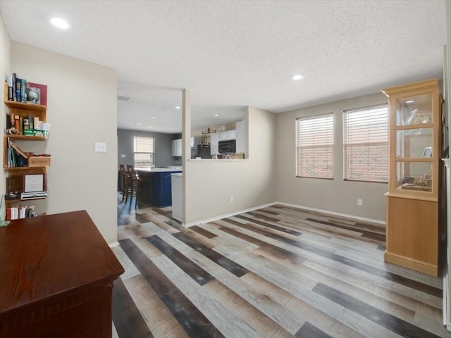 unfurnished living room featuring a textured ceiling and hardwood / wood-style floors