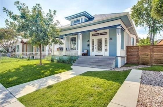 bungalow featuring covered porch and a front yard