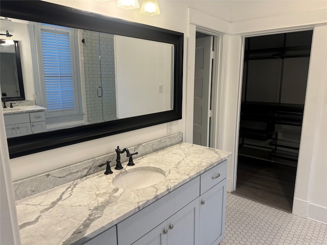 bathroom featuring a shower with shower door, vanity, and tile patterned floors