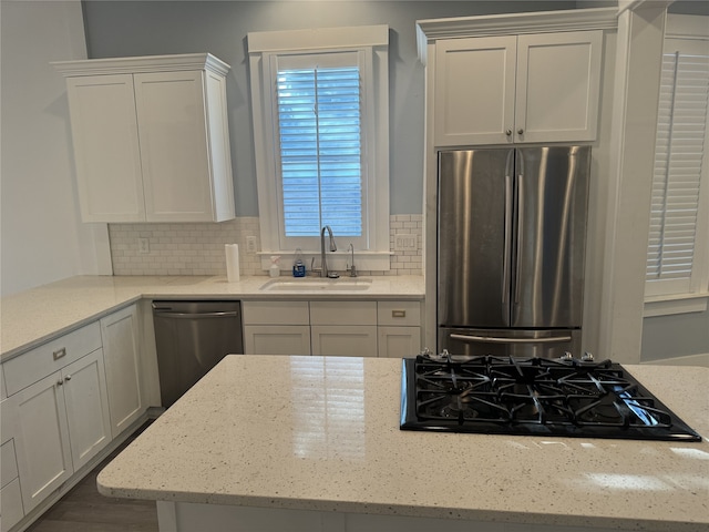 kitchen featuring sink, light stone counters, stainless steel appliances, and white cabinetry