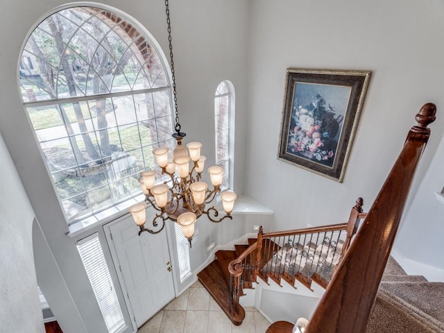 tiled foyer featuring a healthy amount of sunlight, a chandelier, and a high ceiling