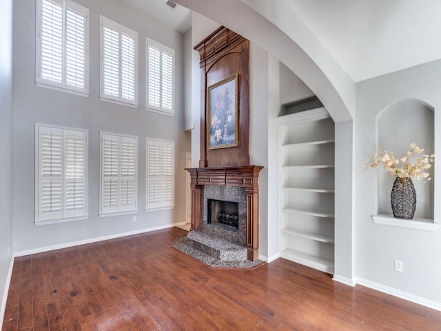 unfurnished living room featuring built in shelves, hardwood / wood-style flooring, and a premium fireplace