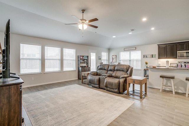 living room with ceiling fan, lofted ceiling, and light wood-type flooring