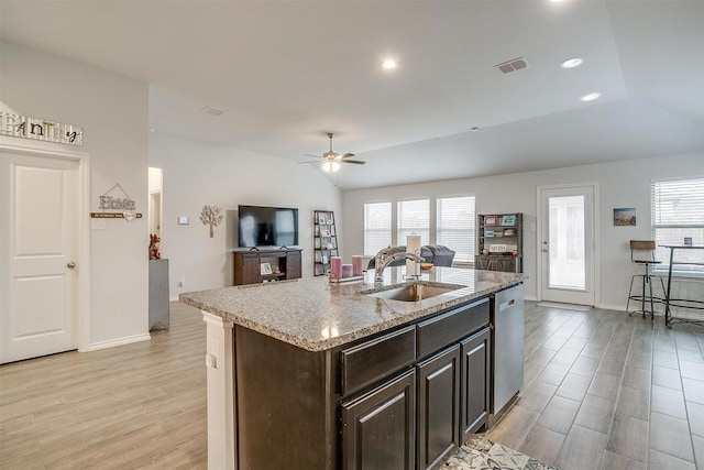 kitchen featuring ceiling fan, vaulted ceiling, dishwasher, sink, and a kitchen island with sink