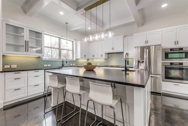 kitchen featuring a kitchen breakfast bar, a center island with sink, beamed ceiling, and appliances with stainless steel finishes