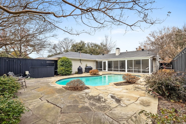 view of swimming pool with grilling area, a patio, and a sunroom