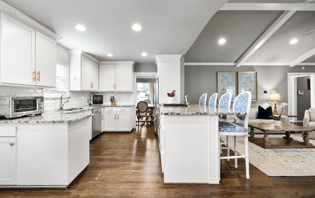 kitchen with white cabinetry, a kitchen bar, light stone countertops, stainless steel dishwasher, and sink