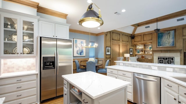 kitchen featuring white cabinetry, a kitchen island, stainless steel appliances, and pendant lighting