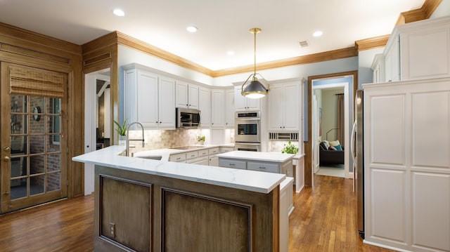 kitchen with white cabinetry, appliances with stainless steel finishes, kitchen peninsula, and decorative light fixtures