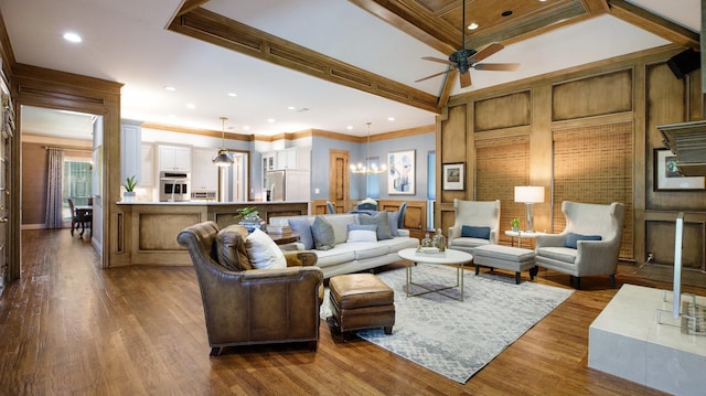 living room featuring dark wood-type flooring, crown molding, and ceiling fan with notable chandelier