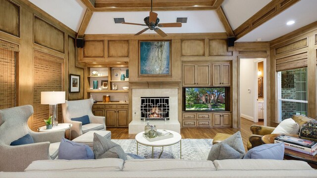 living room with light hardwood / wood-style floors, a tile fireplace, ceiling fan, and wooden walls