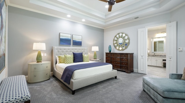 carpeted bedroom with ceiling fan, ensuite bath, crown molding, and a tray ceiling