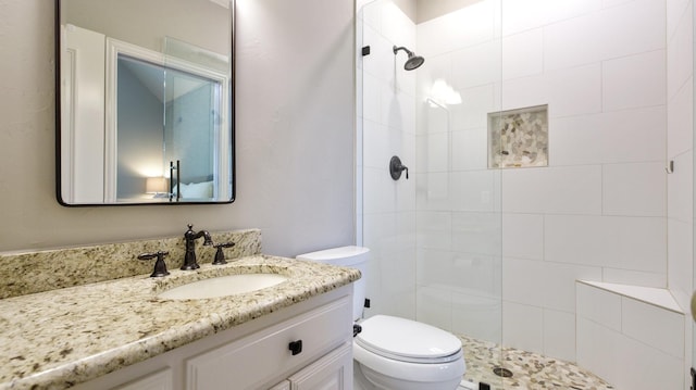 bathroom featuring toilet, vanity, and tiled shower