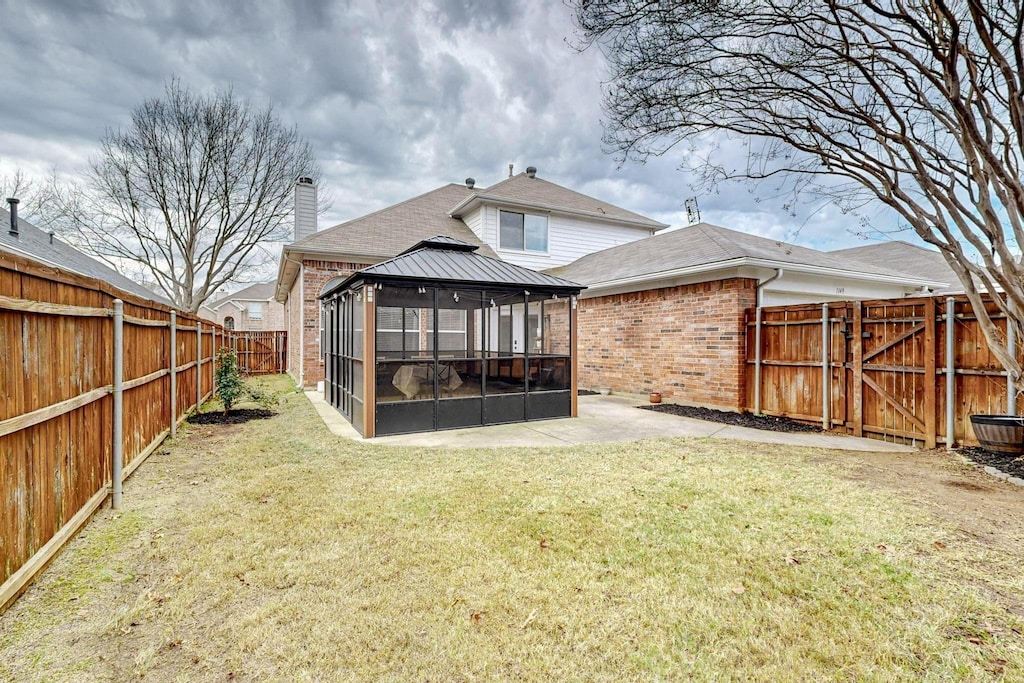 rear view of property with a gazebo, a lawn, and a sunroom