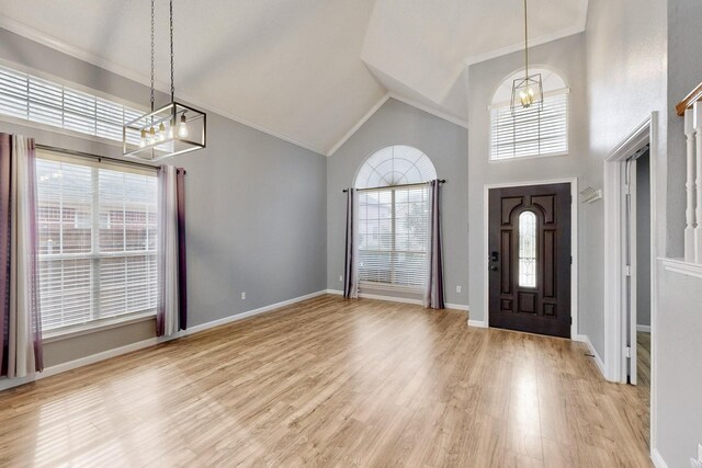 entryway with crown molding, an inviting chandelier, high vaulted ceiling, and light wood-type flooring