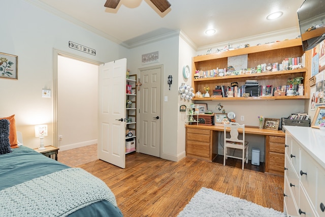 bedroom with ceiling fan, light wood-type flooring, ornamental molding, and built in desk