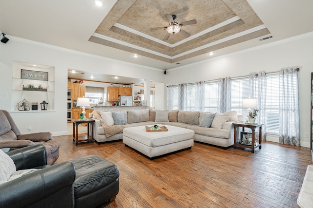 living room with ceiling fan, ornamental molding, hardwood / wood-style floors, and a tray ceiling