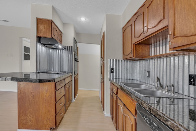 kitchen featuring sink, light hardwood / wood-style flooring, appliances with stainless steel finishes, a kitchen breakfast bar, and a textured ceiling