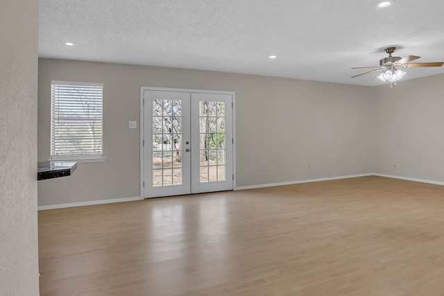 empty room featuring ceiling fan, french doors, a textured ceiling, and light hardwood / wood-style flooring