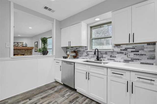 kitchen with tasteful backsplash, dark hardwood / wood-style flooring, stainless steel dishwasher, white cabinets, and sink