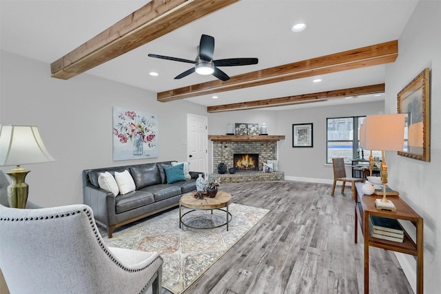 living room featuring a fireplace, beam ceiling, hardwood / wood-style floors, and ceiling fan