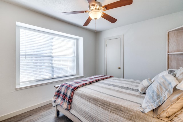 bedroom featuring ceiling fan, multiple windows, and hardwood / wood-style flooring