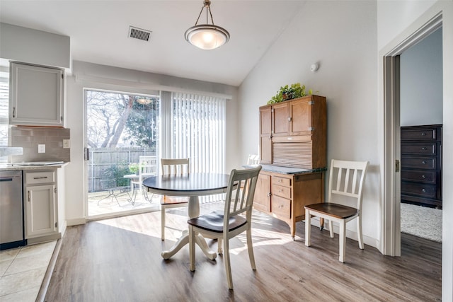 dining area with lofted ceiling and light wood-type flooring