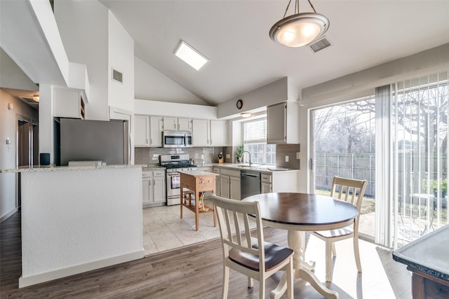 kitchen with appliances with stainless steel finishes, backsplash, hanging light fixtures, a kitchen island, and sink