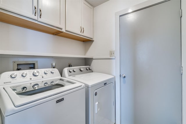 laundry room with washing machine and clothes dryer and cabinets