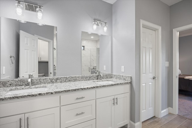 bathroom featuring a shower with shower door and vanity